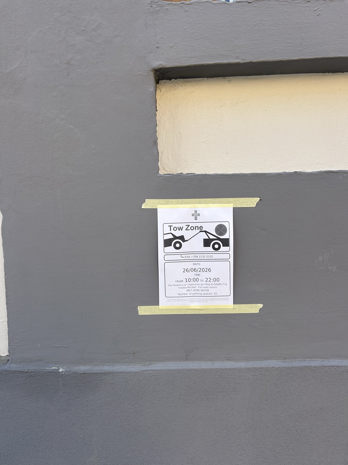 A LESA Tow Zone notice held to a painted wall by two strips of masking tape, dated 26 June 2026.